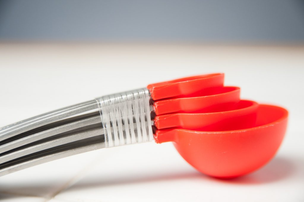 closeup photo of set of metal handle measuring spoons with plastic measuring cups