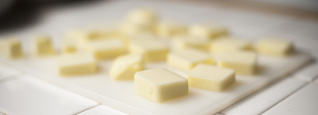 softened pats of butter on white cutting board as part pf crust ingredients