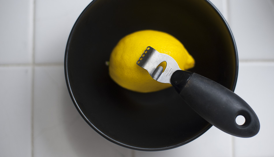 black bowl with lemon and metal zester.  Shows ingedients for lemon zest. 