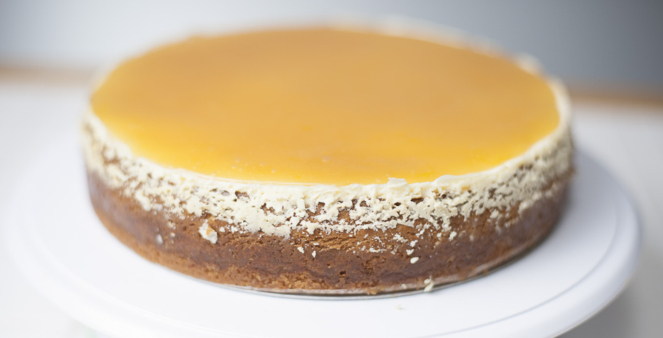 lemon lemon tart cheesecake out of the cheesecake pan showing top layer of lemon curd